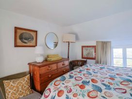A bedroom with a bed, dresser, lamp, and mirror at 2 Oak Tree Cottages, Marshwood Nr. Hawkchurch