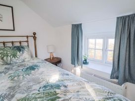 A bedroom with a bed, lamp, and window at 2 Oak Tree Cottages Marshwood Nr. Hawkchurch
