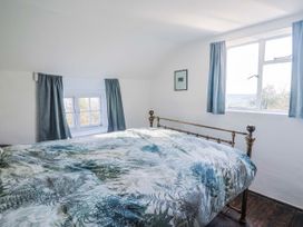A bedroom with a bed and windows at 2 Oak Tree Cottages Marshwood Nr. Hawkchurch