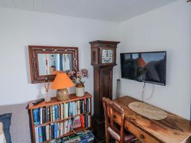 A living room with a clock, desk, lamp, and television at 2 Oak Tree Cottages Marshwood Nr. Hawkchurch