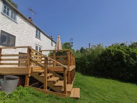 An outdoor area with a wooden deck and umbrella at 2 Oak Tree Cottages in Marshwood Nr. Hawkchurch