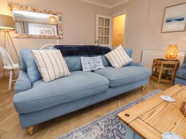 A living room with a blue sofa and decorative cushions at Flat 1, 40 Hinderwell Lane