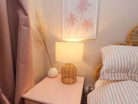 A bedside table with a lamp and decorative plant in a bedroom at Flat 1, 40 Hinderwell Lane