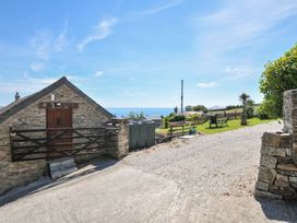 An outdoor area with a stone cottage and sea view at Casa Mia in Porthpean near St Austell