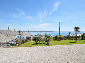 A garden area with a table and chairs overlooking the sea at Casa Mia in Porthpean near St Austell