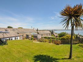 A garden area with a palm tree and ocean view at Casa Mia in Porthpean near St Austell