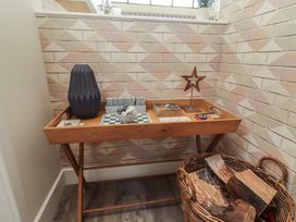 An entryway with a table, vase, and firewood at Summerset Lodge in Bamburgh