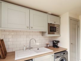 A kitchen with cabinets, sink, microwave, coffee machine, and washing machine at Summerset Lodge, Bamburgh