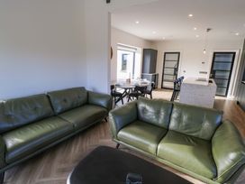 A living room with green sofas and a dining area at An Tobar in Ballina