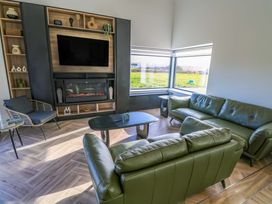 A living room with a TV, sofa, and fireplace at An Tobar in Ballina