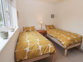 A bedroom with two beds and a lamp at Pump Cottage in Truro