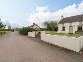 A house with a green door and fence on a road at Beacon House Marloes near Little Haven