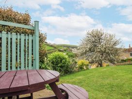 A garden with a wooden table and a tree at Quay Sands, Hope Cove