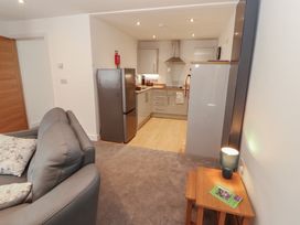 A living room with a sofa and kitchenette at Little Plumtree in Milnthorpe