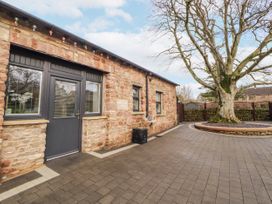 An outdoor view of a stone building with a patio at Blue Heron Lodge in Kirkby Stephen