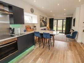A kitchen with bar stools and a dining table at Blue heron lodge in Kirkby Stephen