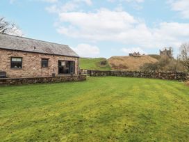 A garden with a stone house and lawn at Blue Heron Lodge in Kirkby Stephen