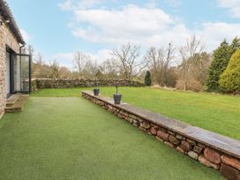 A garden with grass and stone wall at Blue heron lodge in Kirkby Stephen