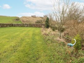 A garden with grass and a stone wall at Blue Heron Lodge Kirkby Stephen