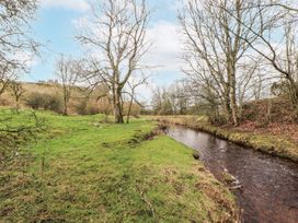 A stream with trees and grass near ruins at Blue Heron Lodge in Kirkby Stephen