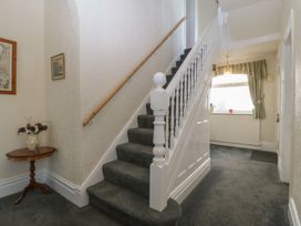 A hallway with a staircase and a small table with a vase at Gwynfa in Old Colwyn