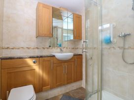 A bathroom featuring a sink, toilet, shower, and cabinets at Gwynfa in Old Colwyn