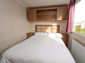 A bedroom with a bed and window at Caravan B14 Beechrise in Filey