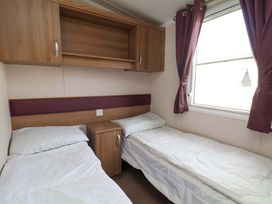 A bedroom with two beds and a shelf at Caravan B14 Beechrise Filey