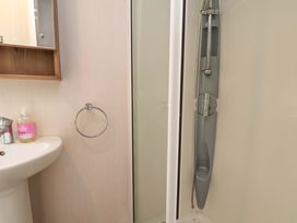 A bathroom with a washbasin, mirror, towel ring, and shower at Caravan B14 Beechrise, Filey
