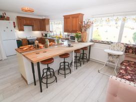 A kitchen with wooden cabinets and stools at Piskies Magic Home 