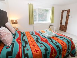 A bedroom with a bed, colorful bedspread, and window at Piskies Magic Home
