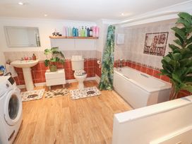 A bathroom with a sink, toilet, bath tub, and washing machine at Piskies Magic Home