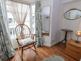 A bedroom with a rocking chair and mirror at 1 Alpha Cottages in Tenby