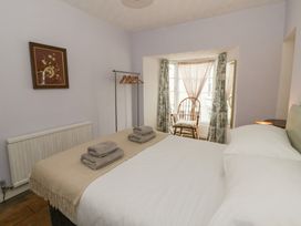A bedroom with a bed and chair at 1 Alpha Cottages in Tenby