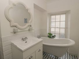 A bathroom featuring a bathtub, sink, and mirror at 1 Alpha Cottages Tenby