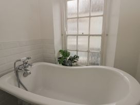A bathroom with a bathtub and window at 1 Alpha Cottages in Tenby
