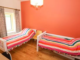 A bedroom with two beds and a chair at The Cottage in Leenane, County Galway