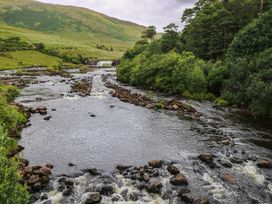 A river with rocks and trees at The Cottage in Leenane, County Galway