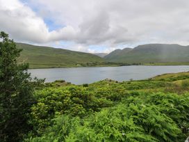 A view of a lake surrounded by mountains and vegetation at The Cottage in Leenane, County Galway