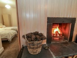 A bedroom with a fireplace and basket of firewood at Hanowen House in Dungloe, County Donegal