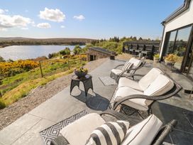 An outdoor patio with chairs and a table overlooking a lake at Hanowen House in Dungloe, County Donegal