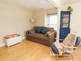 A living room featuring a sofa, armchair, coffee table, and bookcase at Flat 3