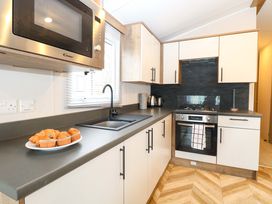 A kitchen with a sink, cooker, microwave, and muffins at Caravan in Great Yarmouth