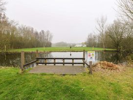 A pond with a wooden platform and a warning sign at the outdoor area of a caravan site in Great Yarmouth
