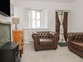 A living room with sofas, a lamp, and a door at Fellfoot Cottage