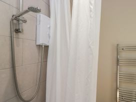 A shower with a curtain and heating towel rail at Fellfoot Cottage