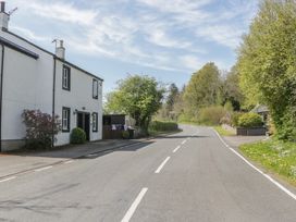 A house beside a road with trees and hedges at Fellfoot Cottage in 