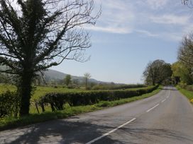 A road lined with trees and hedges near a field at Fellfoot Cottage