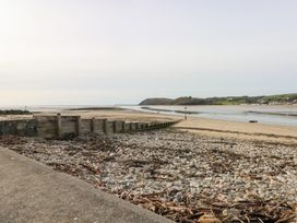 A beach with a wooden barrier and pebbles at Under cliff caravan in Ferryside