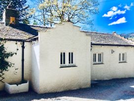 A cottage exterior with trees and a pathway at The Dove Cot in Ambleside